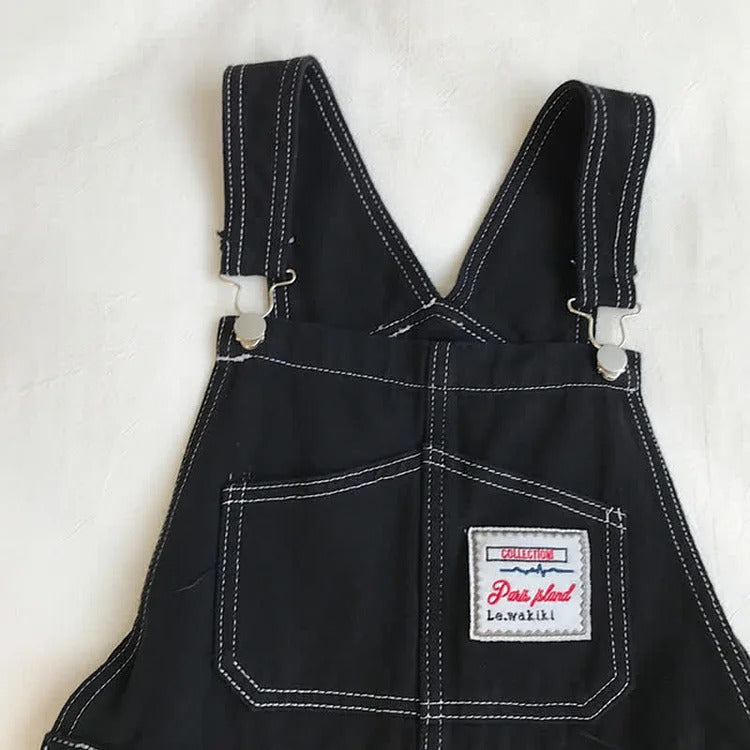 Black denim overall dress with white stitching detail, long sleeves, and adjustable straps. Part of a two-piece set.