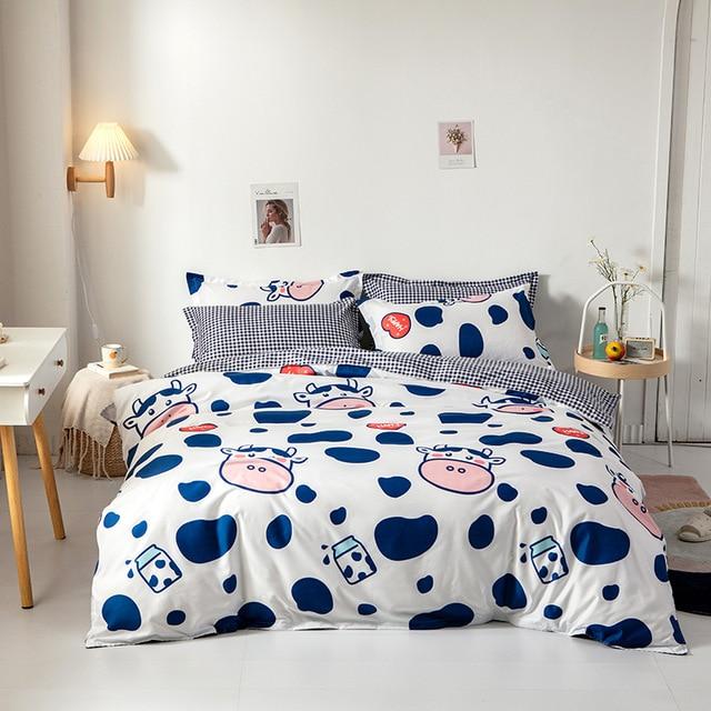 Adorable cow and milk cartoon bedding set; soft, breathable polyester microfiber; reversible design; includes duvet cover, flat sheet, and pillowcases.