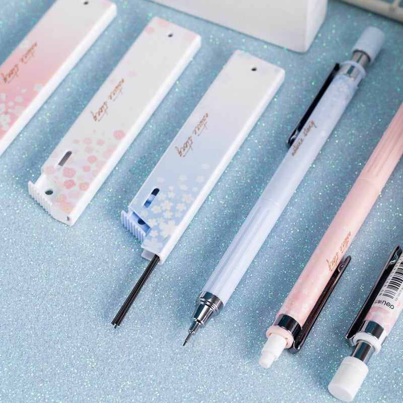 Three pastel Deli Sakura 0.5mm mechanical pencils with cherry blossom design; smooth writing, durable plastic.