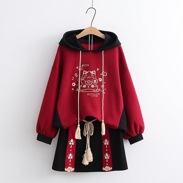 Red & black Harajuku lucky cat hoodie and mini skirt set; soft cotton blend, embroidered details, drawstring hoodie, and tassel belt.