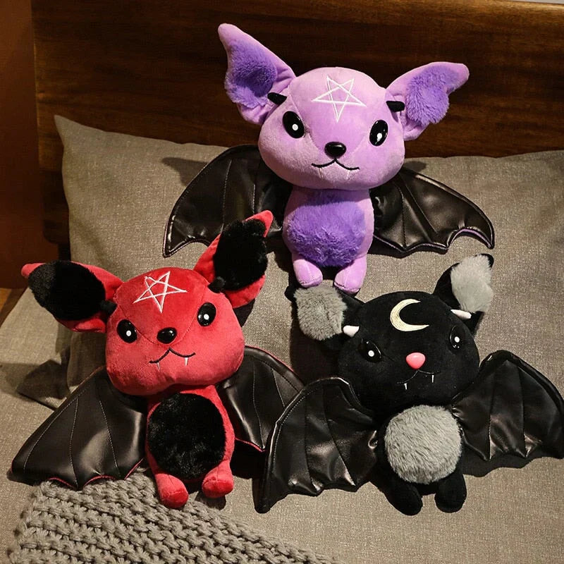 Kawaii bat plushies with pentagram or moon design, black faux leather wings, and soft PP cotton filling.  Available in red, purple, and black.