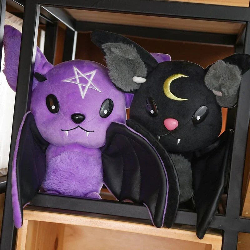 Kawaii bat plushies; purple with pentagram, black with crescent moon; soft PP cotton; faux leather wings; Halloween goth decor.