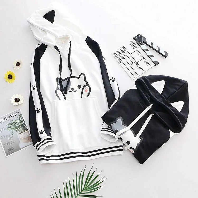 Kawaii kitty paw print hoodie in white and black polyester. Features long sleeves, a hooded neckline, and cute cartoon design. One size fits most.