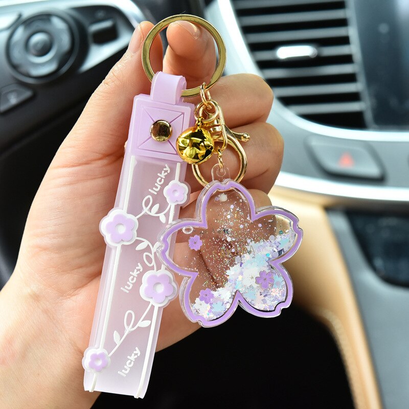 Lavender Sakura cow quicksand keychain with gold accents, resin & zinc alloy, features glitter & floral design.