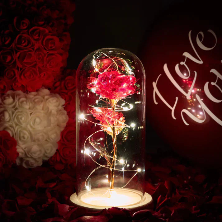 Illuminated iridescent rose preserved in glass dome with warm LED lights & wooden base; perfect romantic gift.