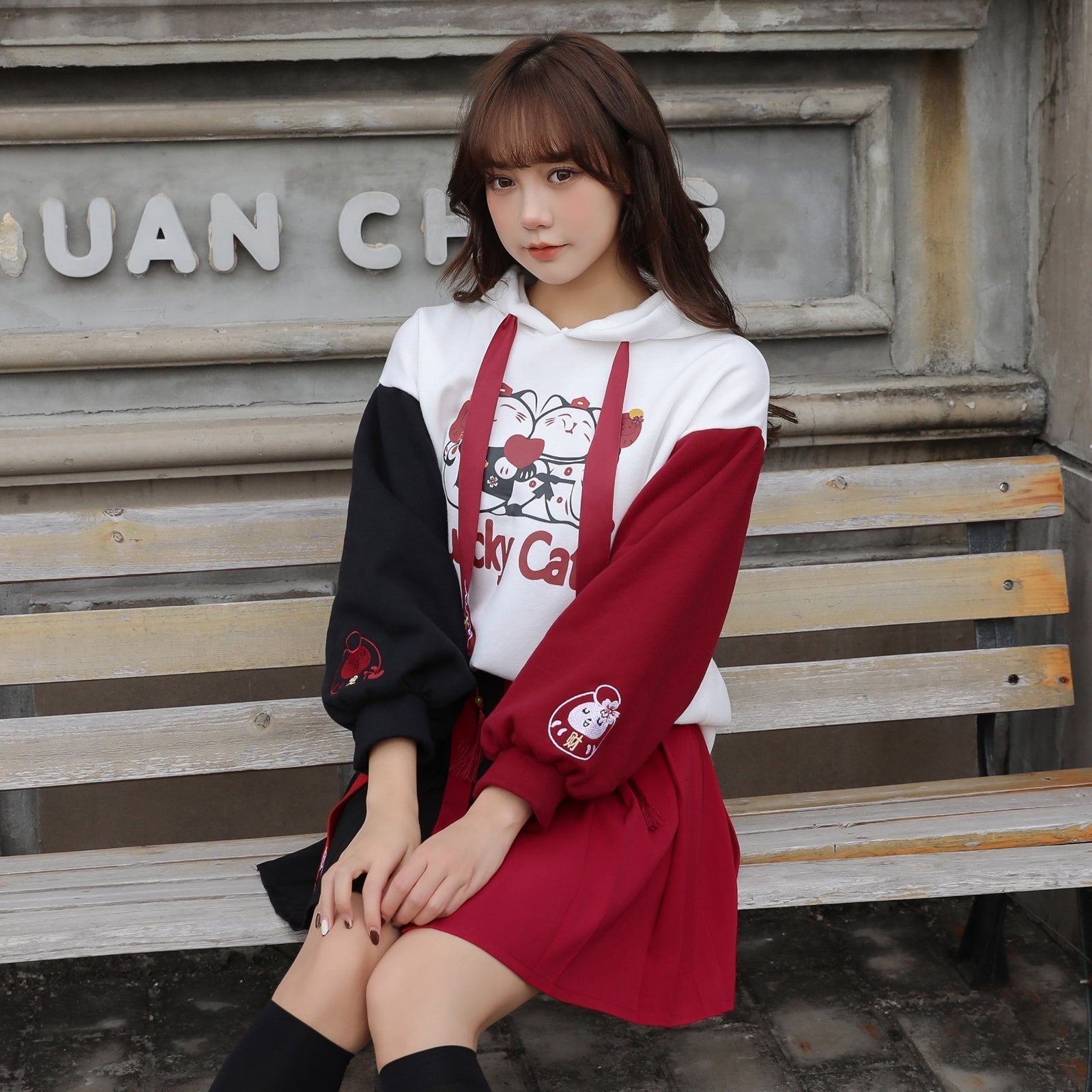 Red & black colorblock lucky cat hoodie & mini skirt set; features cartoon cat print, tassels, and cat paw embroidery.