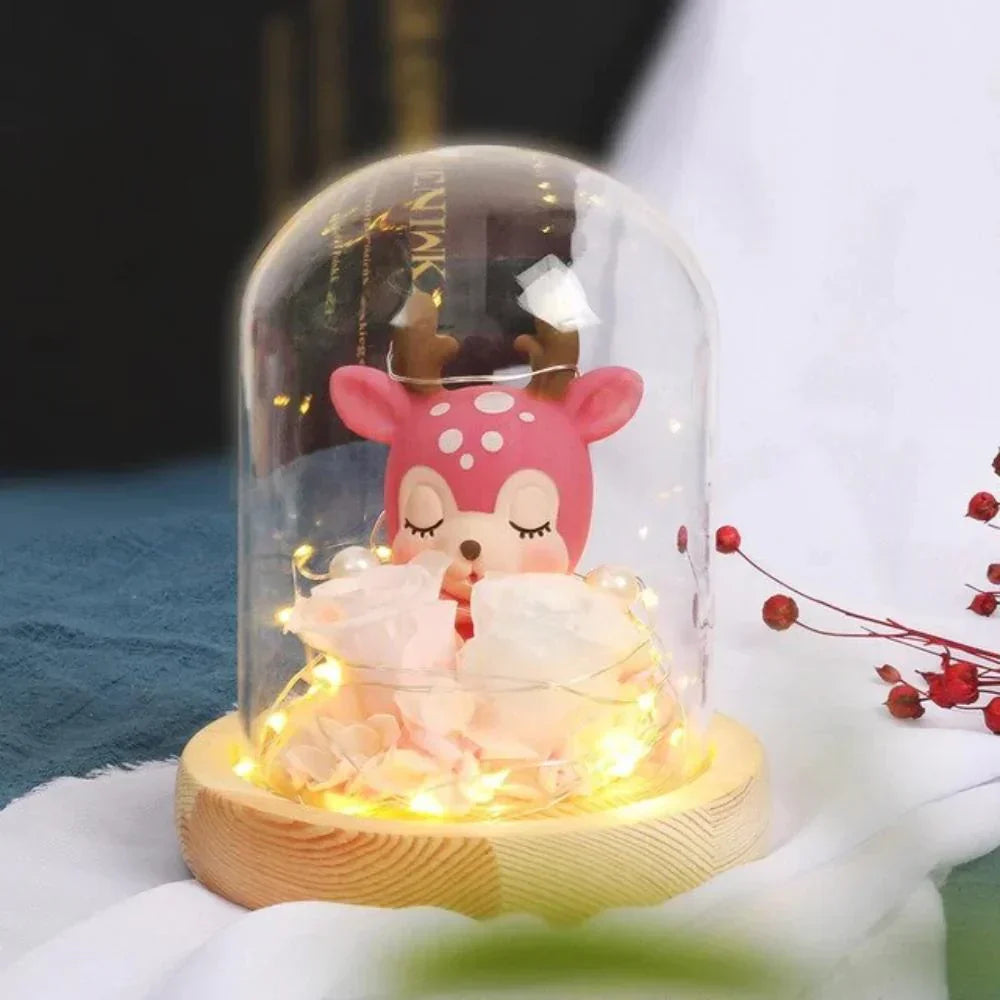 Pink deer figurine & preserved roses in glass dome with warm LED lights; charming décor or gift.