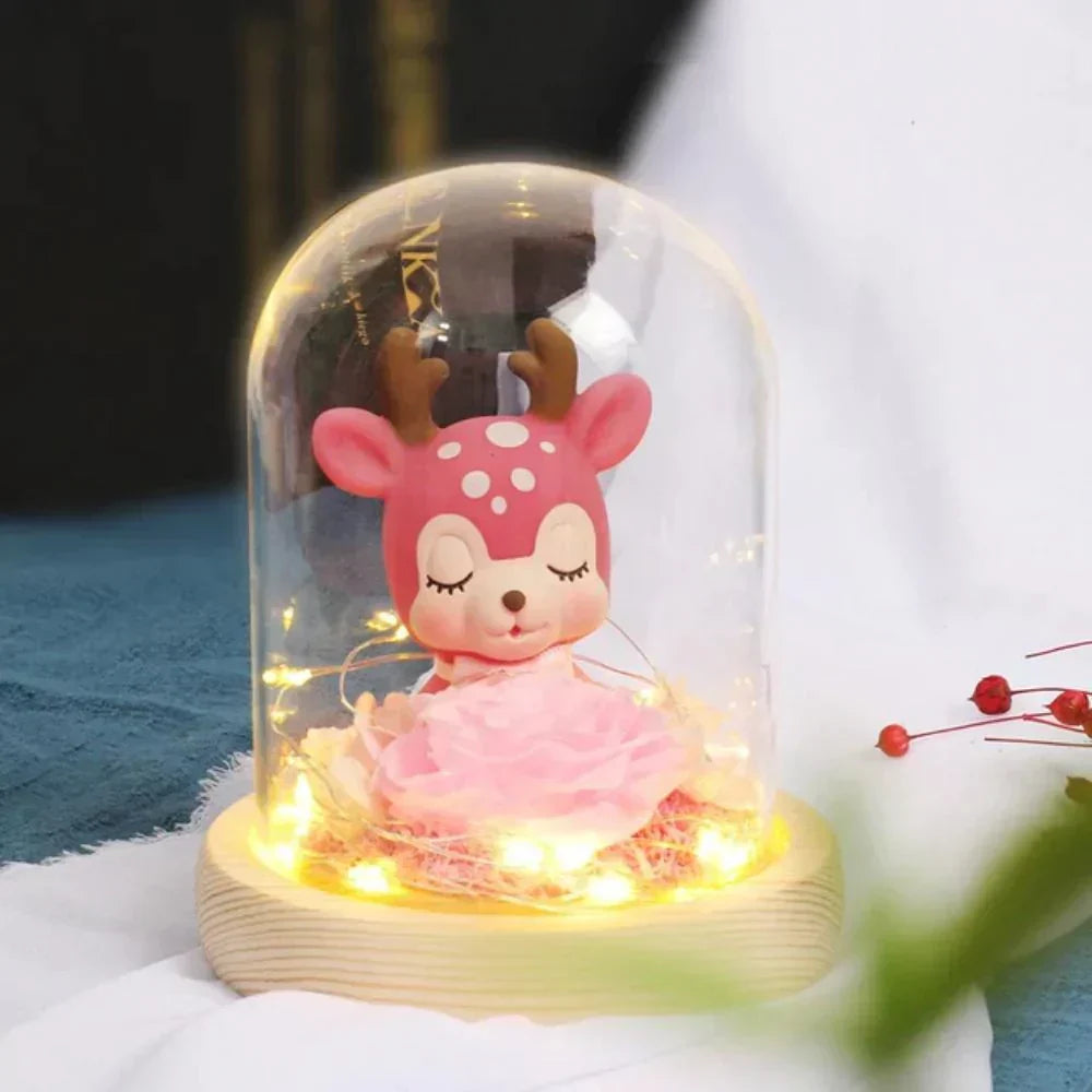 Pink deer figurine & preserved pink rose in glass dome with warm LED lights; charming home décor or gift.