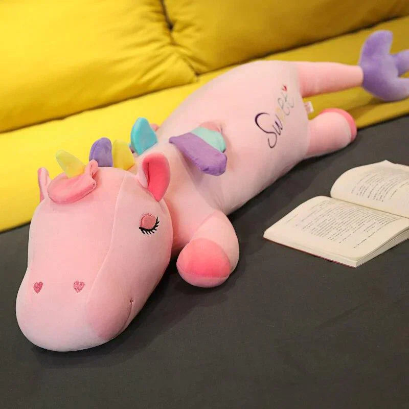 Pink giant unicorn plush body pillow with rainbow mane, pastel wings, and "Sweet" embroidery.  Soft PP cotton filling.