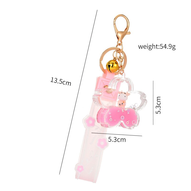 Pink sakura cow quicksand keychain with gold accents, bell charm, and glitter; resin and zinc alloy.