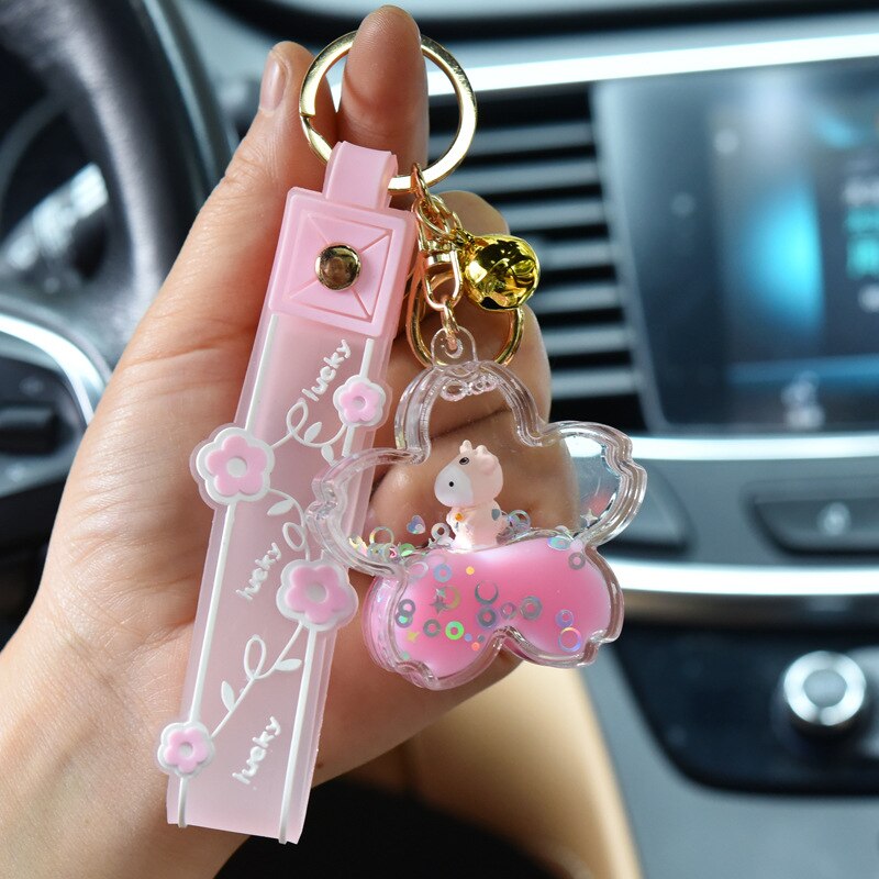 Pink sakura cow quicksand keychain with gold accents, resin and zinc alloy, flower-shaped charm.