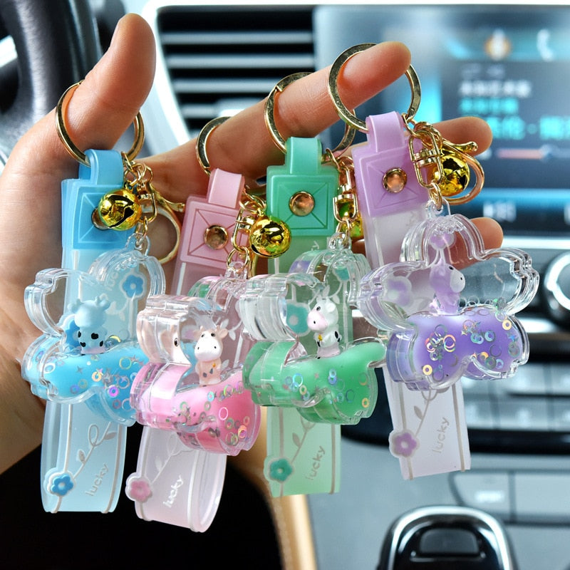 Cute pink sakura cow quicksand keychain with gold accents; resin and zinc alloy; mesmerizing glitter inside.