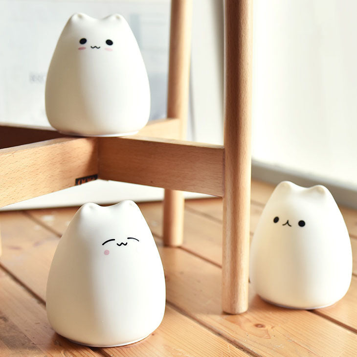 Adorable white silicone cat night light; color-changing LED, 3 cute designs. Soft, calming ambiance for bedrooms.