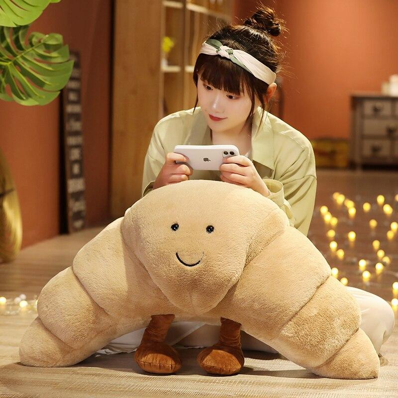 Tan curly croissant plush toy with smiling face, soft PP cotton filling, available in small, medium, and large sizes.