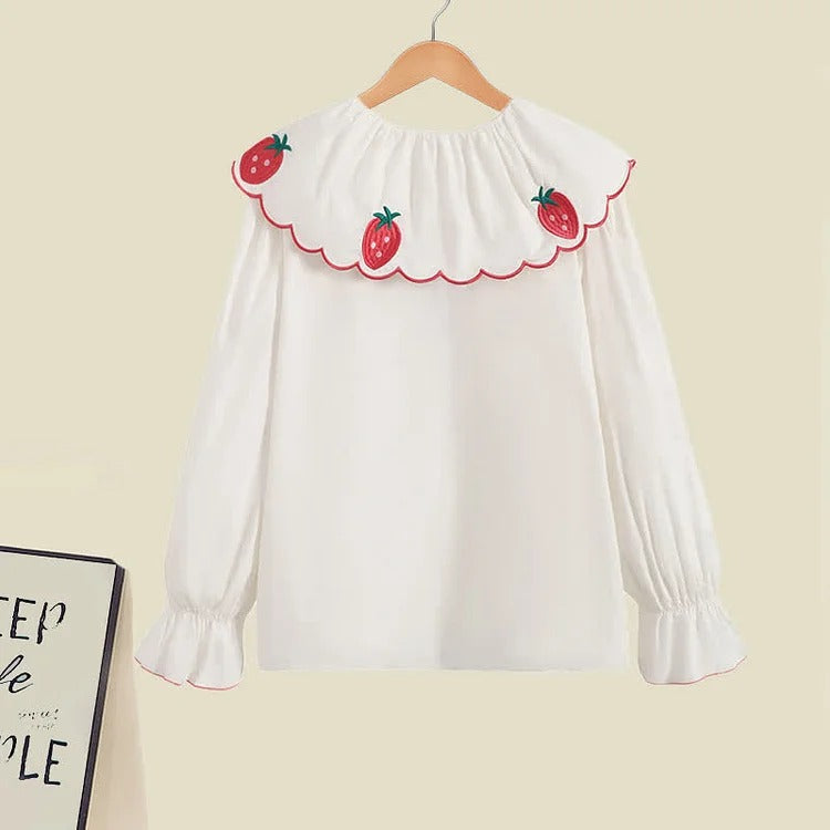 White polyester blouse with strawberry embroidery, peter pan collar, and long sleeves.