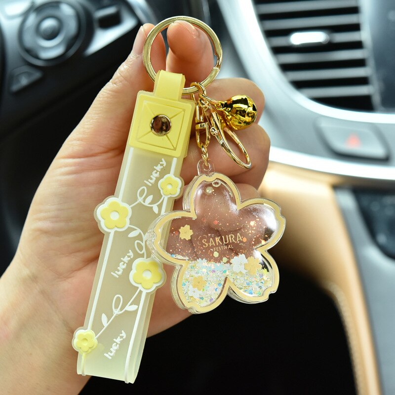 Cute yellow Sakura flower quicksand keychain with gold accents,  featuring a cow design and shimmering glitter.